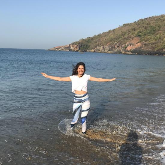 Tanvi holding her arms out wide, standing in the sea