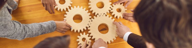 Hands placing wooden cogs onto a table